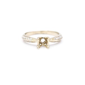 May include: A gold engagement ring setting with a pave diamond band. The setting is designed to hold a center stone.