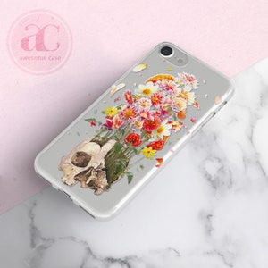 May include: A clear phone case with a skull design and a bouquet of colorful flowers growing out of the top of the skull.
