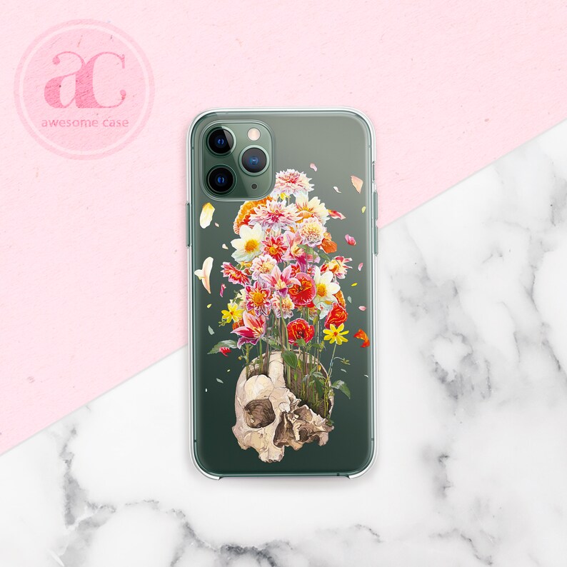 May include: A clear phone case with a green background and a skull with flowers growing out of it. The flowers are red, pink, yellow, and white.