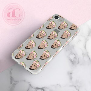 Op de afbeelding: Transparante telefoonhoes met een herhalend patroon van een mannengezicht met een roze bloemenkrans. De hoes is ontworpen voor een iPhone.