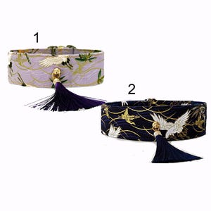 May include: Two decorative collars with Japanese-inspired designs. One is lavender with gold accents and a crane motif, the other is navy blue with white cranes and gold details. Both have a dark purple tassel.