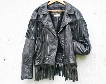 May include: Black leather jacket with fringe detailing. The jacket has a zipper closure and a label that reads "Ranch Leather Co."