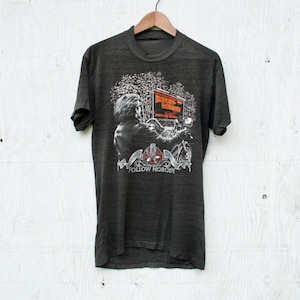 May include: A dark gray t-shirt with a graphic print of a person riding a Harley Davidson motorcycle. The graphic includes the text "Harley Davidson" and "Follow Nobody".