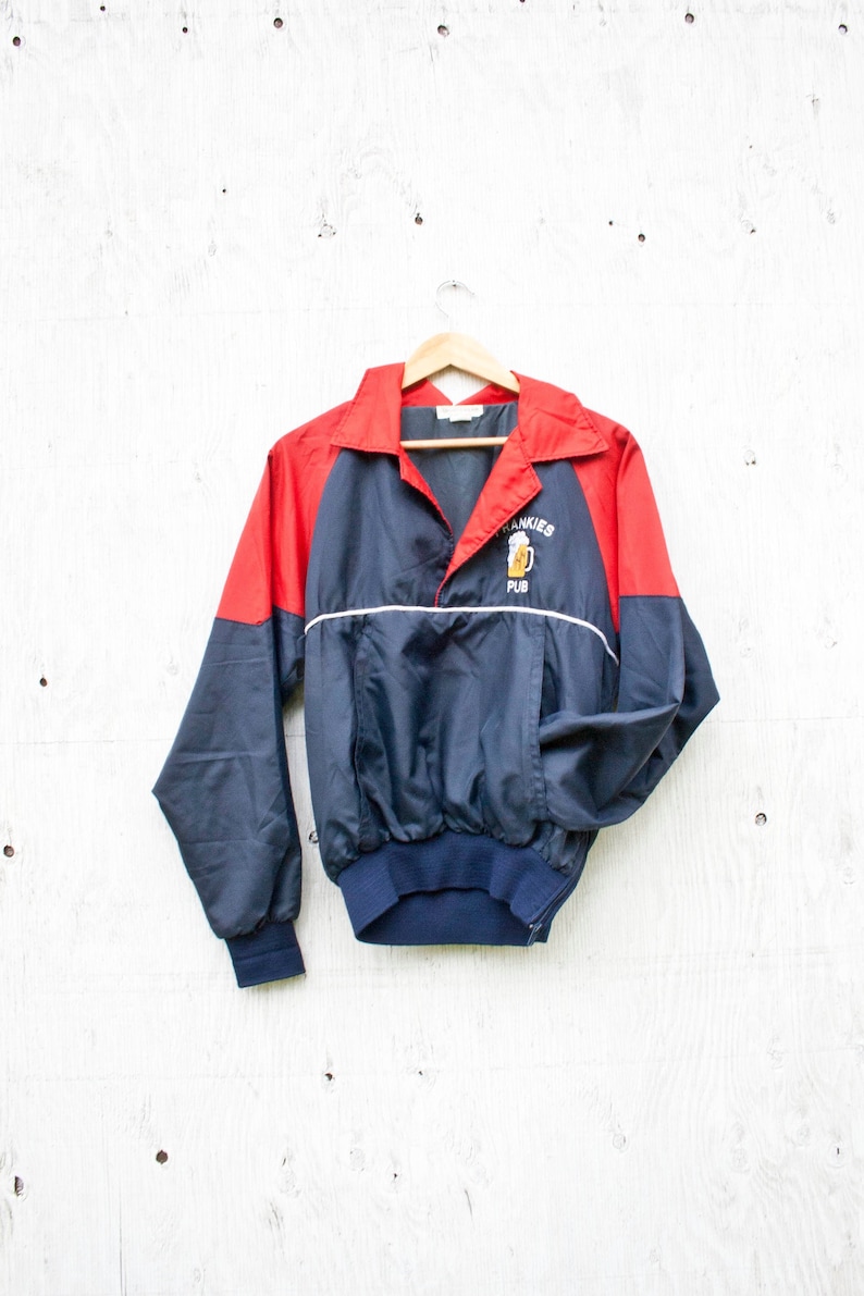 May include: A blue and red windbreaker jacket with a white stripe and the text "Tankies Pub" embroidered on the front.