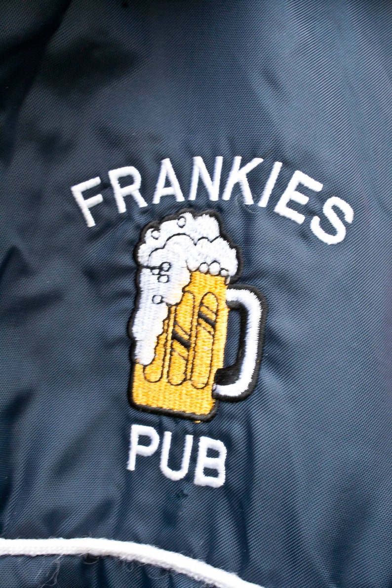 May include: A blue embroidered patch with the text "FRANKIES PUB" and a cartoon image of a beer mug with foam on top.