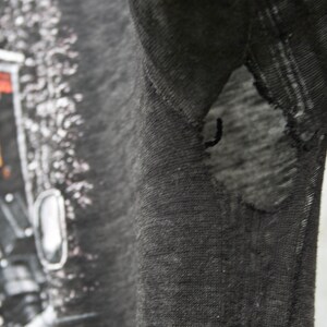 May include: Black t-shirt with a Harley Davidson graphic print. The shirt has a small tear on the right sleeve.
