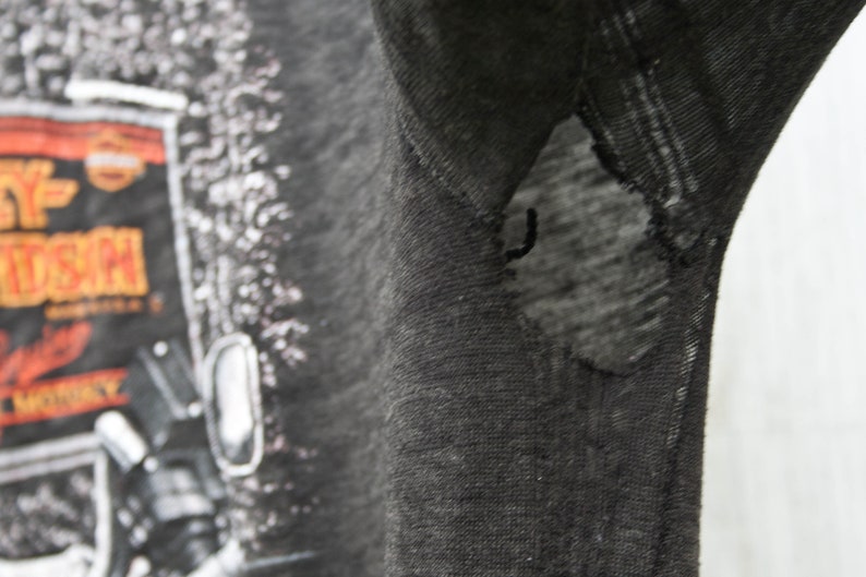 May include: Black t-shirt with a Harley Davidson graphic print. The shirt has a small tear on the right sleeve.