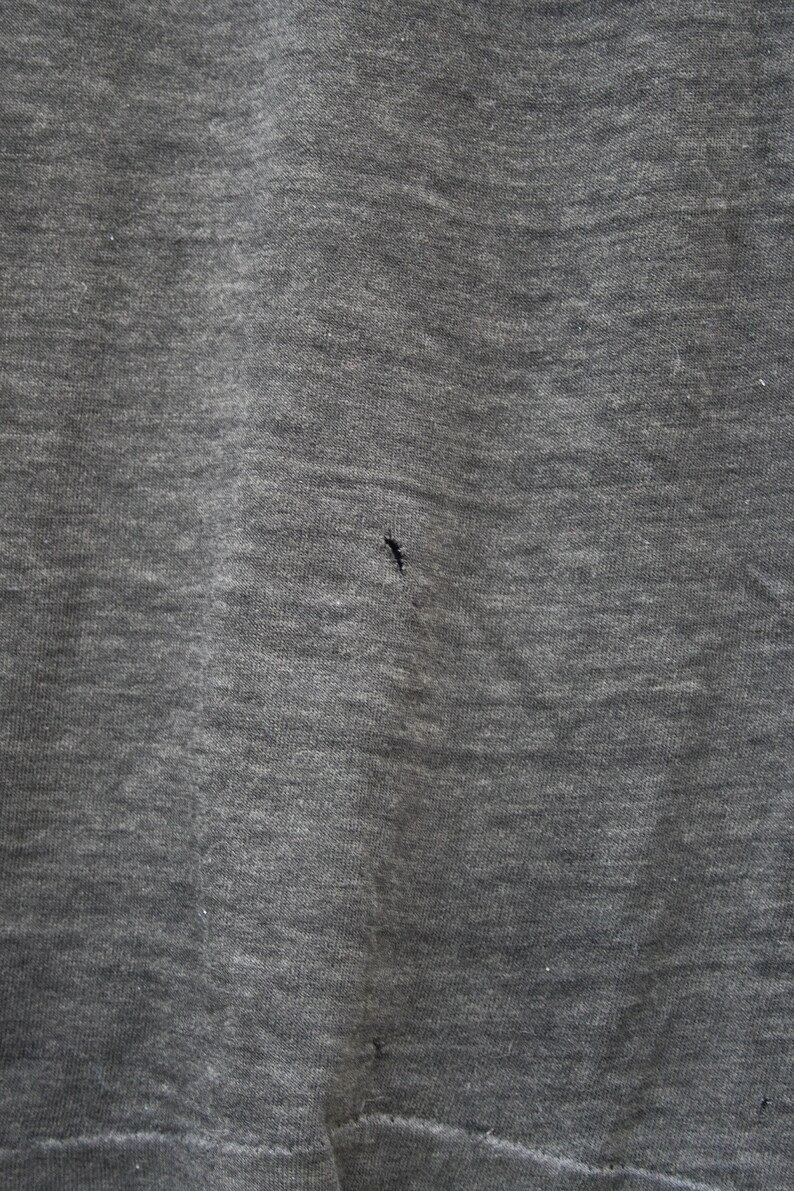 May include: A close-up of a gray fabric with a small hole in the center.