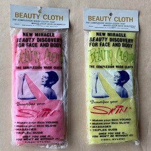 May include: Two packages of pink and yellow nylon washcloths. The packages feature a woman's face and the text "New Miracle Beauty Discovery for Face and Body" and "Beauty Cloth The Complexion Wash Cloth".