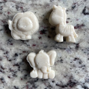 May include: Three white, animal-shaped, silicone molds. The molds are shaped like a lion, a zebra, and an elephant.