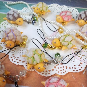 Op de afbeelding: Een verzameling handgemaakte schildpadbedels van polymer clay met verschillende gekleurde glazuurontwerpen. Elke schildpadbedel heeft een gouden lus om aan een sleutelhanger of tas te bevestigen.