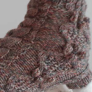 May include: Close-up of a knitted brown, pink, and gray cable knit sock with a textured pattern.
