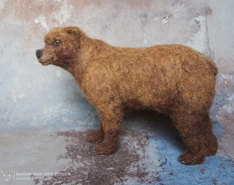May include: A brown needle felted bear sculpture. The bear is standing on a light blue and gray textured surface.