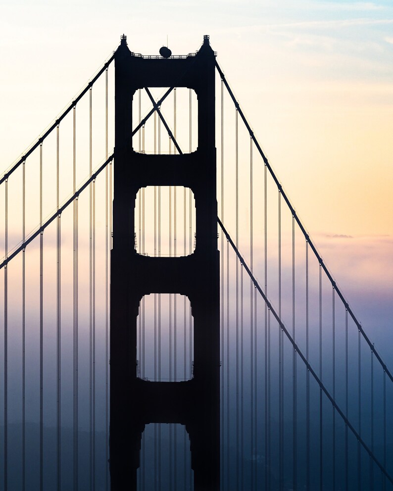 May include: A silhouette of the Golden Gate Bridge against a colorful sunrise sky. The bridge is made of steel and has a distinctive orange color. The bridge is a popular tourist destination in San Francisco, California.