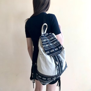 May include: A white ceramic mug with a black handle and the text "But First, Coffee" in a bold, black font. The mug is set against a blurred background, suggesting a cosy setting.