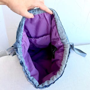 Op de afbeelding: Denim trekkoordtas met een levendig paarse binnenkant. De binnenkant van de tas heeft een klein vak. De tas is gemaakt van denim materiaal en heeft een trekkoord sluiting.