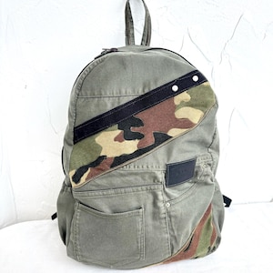 Op de afbeelding: Olijfgroene rugzak met camouflage accent. De rugzak heeft een zwarte band en een kleine zwarte leren patch. Het heeft een voorvak en een handvat aan de bovenkant. Gemaakt van een duurzame stof.