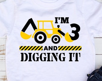 Puede incluir: Camiseta blanca con un gráfico de vehículo de construcción amarillo y el texto "Tengo 3 años y me encanta".