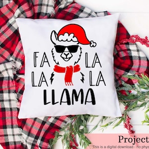 Può includere: Cuscino bianco con un'illustrazione in bianco e nero di un lama che indossa un cappello da Babbo Natale rosso e occhiali da sole. Il testo "Fa La La Llama" è stampato in nero.