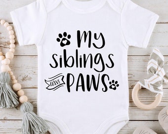 May include: White baby onesie with black text that reads "My siblings have paws" with a paw print graphic.