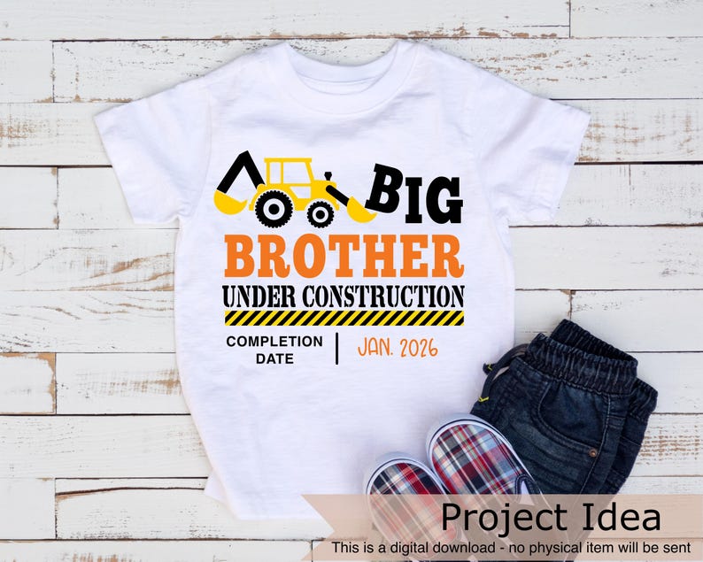 May include: A white t-shirt with a yellow construction vehicle graphic and the text "BIG BROTHER UNDER CONSTRUCTION" with a yellow and black striped banner below that says "COMPLETION DATE | JAN. 2026".