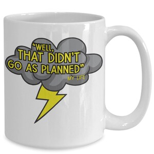 Puede incluir: Taza de café de cerámica blanca con un gráfico de nube de tormenta negro y gris y un rayo amarillo. El texto "Well, that didn't go as planned" está escrito en amarillo en la nube. El texto "My Life" está escrito en amarillo más pequeño debajo de la nube.