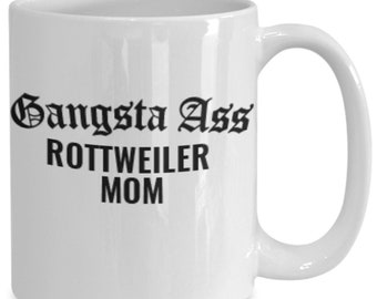 May include: White ceramic mug with the text "Gangsta Ass Rottweiler Mom" in black gothic lettering. The mug has a curved handle and is designed for hot beverages.