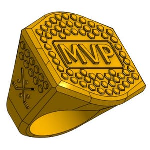 May include: A gold-colored ring with the letters "MVP" in a rectangular frame. The ring's top surface features a honeycomb pattern and the side has a hockey stick and puck design. The ring is a symbol of achievement and recognition.