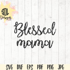 May include: Black and white distressed text graphic design that reads "Blessed mama" on a white wood background.
