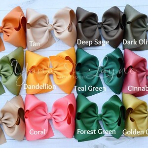 May include: Twelve large hair bows in various colors, including ginger, tan, deep sage, dark olive, olive, dandelion, teal green, cinnabar, latte, coral, forest green, and golden olive.