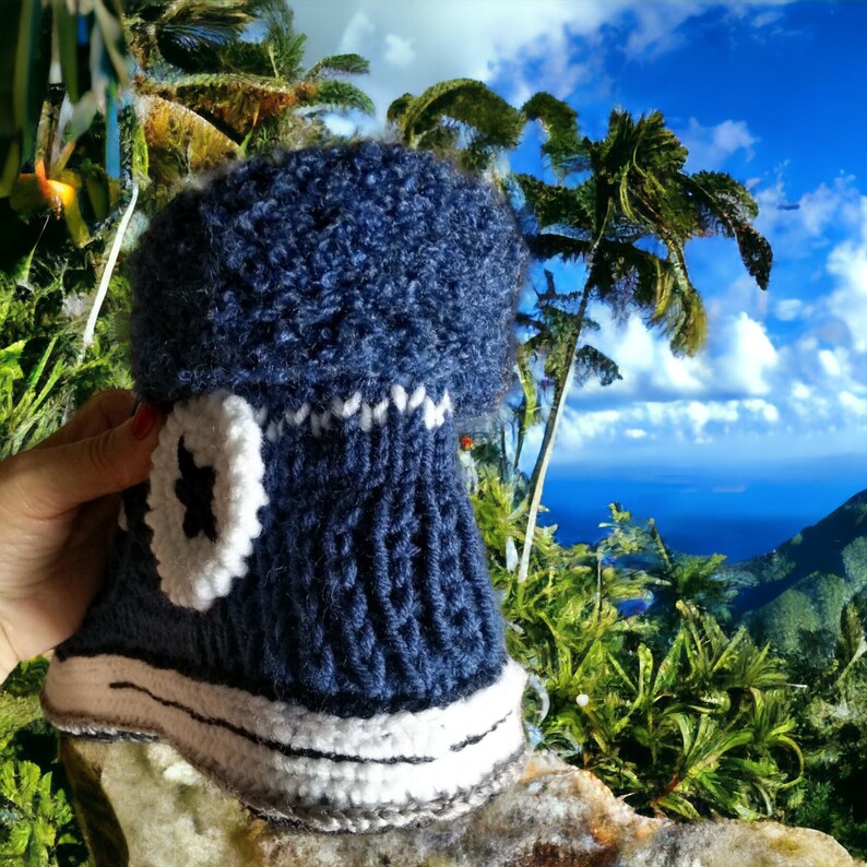 A blue knitted hat shaped like a converse shoe with white trim and a white star on the side.