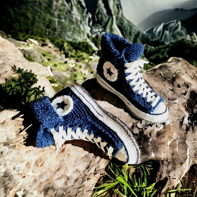 Two blue and white knitted sneakers with white laces and a white star on the side.