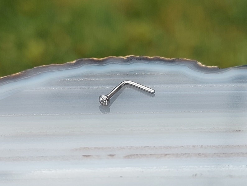May include: A silver nose ring with a small clear gemstone.
