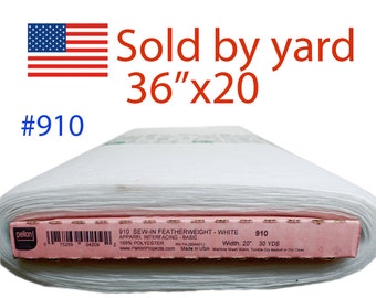 May include: White fabric roll with a pink label. The label reads "910 SEW-IN FEATHERWEIGHT - WHITE" and "Width: 20" 30 YDS". The text "Sold by yard 36"x20" is in red. An American flag is in the upper left corner.