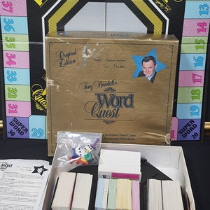 May include: A vintage "Word Quest" board game, "Original Edition", with a gold-colored box. The box features the game's title, the name "Tony Randall", and a star-shaped image. Inside, there are game cards, dice, and game pieces.
