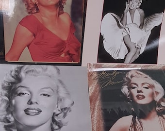 May include: Collection of Marilyn Monroe memorabilia, including calendars and portraits. The images feature the actress in various poses, with a focus on her iconic style. The color palette includes red, black, and white, with some images in sepia tones.