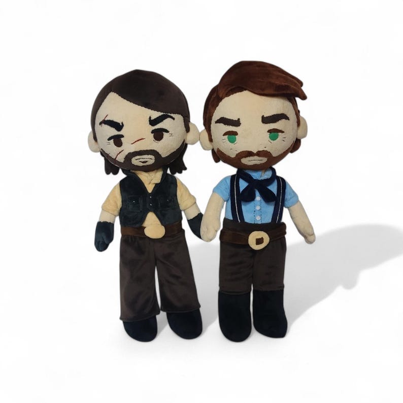 Puede incluir: Dos mu&ntilde;ecos de peluche de figuras masculinas, cada uno con un dise&ntilde;o distintivo. Un mu&ntilde;eco viste un chaleco negro sobre una camisa beige y pantalones marrones. El otro mu&ntilde;eco viste una camisa azul con tirantes y pantalones marrones. Ambos mu&ntilde;ecos tienen barba y se dan la mano.