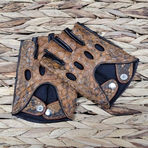 May include: A pair of brown leather fingerless gloves with a snakeskin pattern. The gloves have a black leather trim and a snap closure.