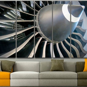 May include: A close-up of a jet engine with a silver and black colour scheme. The engine is made up of many blades that are arranged in a circular pattern. The blades are partially obscured by the engine's casing, which is also silver and black.