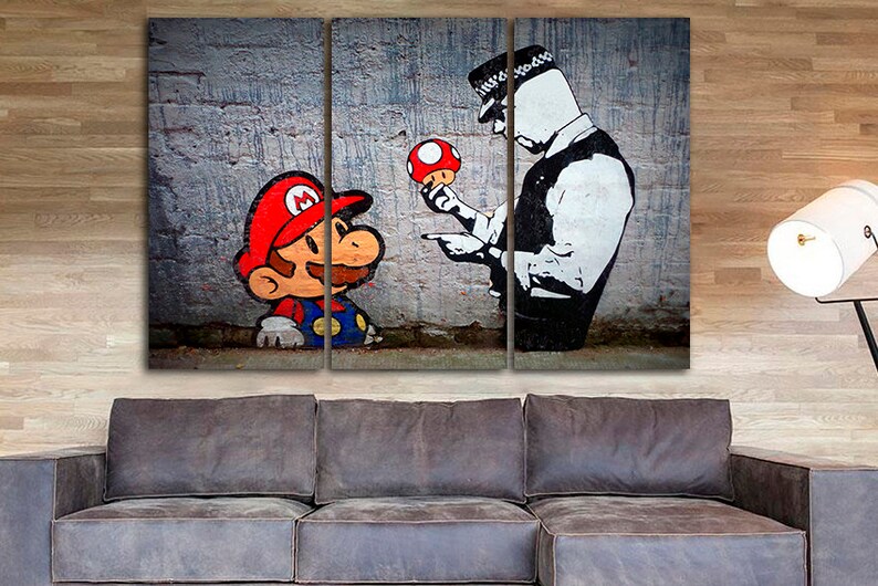 Pu&ograve; includere: Una stampa su tela a tre pannelli con un'illustrazione in bianco e nero di un poliziotto che tiene un fungo rosso e punta il dito verso un personaggio dei cartoni animati che assomiglia a Mario, che indossa un cappello rosso e una salopette blu.
