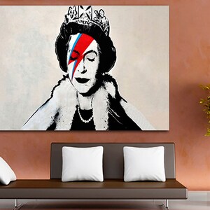 May include: A black and white portrait of Queen Elizabeth II with a red, blue, and white lightning bolt painted across her right eye. The queen is wearing a crown and a fur collar.
