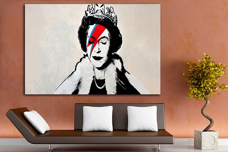 May include: A black and white portrait of Queen Elizabeth II with a red, blue, and white lightning bolt painted across her right eye. The queen is wearing a crown and a fur collar.