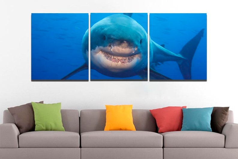 May include: A three-panel canvas print featuring a close-up of a great white shark with its mouth open, showing its teeth. The shark is swimming in blue water.