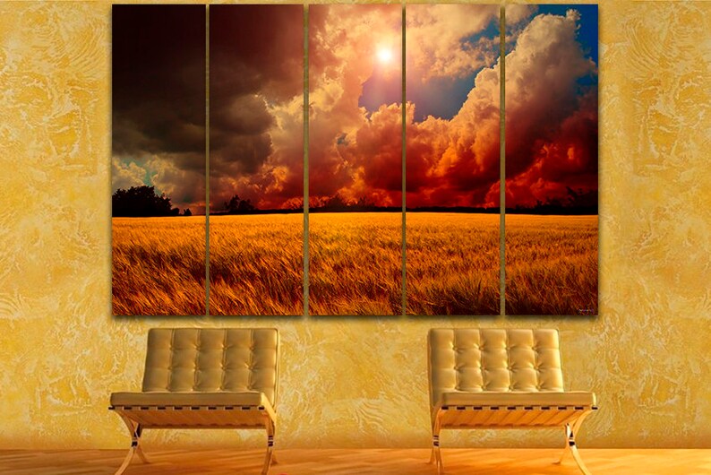 K&ouml;nnte beinhalten: Ein f&uuml;nfteiliger Leinwanddruck, der eine dramatische Landschaft zeigt. Das Kunstwerk zeigt ein goldenes Weizenfeld unter einem feurigen Himmel mit dunklen Wolken und einer hellen Sonne. Zwei goldfarbene St&uuml;hle stehen vor einer strukturierten gelben Wand.