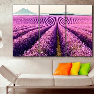 May include: A three-panel canvas print featuring a field of purple lavender flowers. The lavender field is in rows and the rows are lined up in a perspective that leads the eye to the horizon. The horizon is in the distance and there are hills in the background.