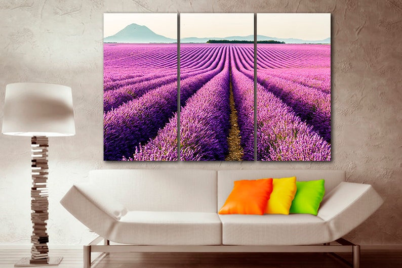 May include: A three-panel canvas print featuring a field of purple lavender flowers. The lavender field is in rows and the rows are lined up in a perspective that leads the eye to the horizon. The horizon is in the distance and there are hills in the background.