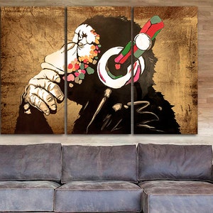 Op de afbeelding: Een driedelig canvasprint met een gestileerde afbeelding van een aap die een koptelefoon draagt met kleurrijke accenten. De achtergrond is van een textuur in goudkleur.