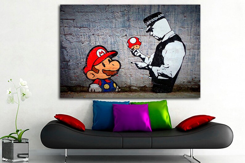 Pu&ograve; includere: Una stampa d'arte graffiti in bianco e nero di un poliziotto che tiene un fungo rosso e punta il dito verso un personaggio dei cartoni animati di Mario. Lo sfondo &egrave; un muro di mattoni grigi.