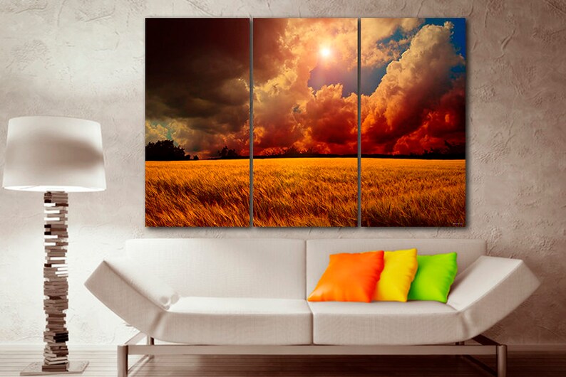 K&ouml;nnte beinhalten: Ein dreiteiliger Leinwanddruck, der eine dramatische Landschaft zeigt. Das Kunstwerk zeigt ein goldenes Feld unter einem feurigen Himmel mit dunklen, bedrohlichen Wolken. Die Sonne scheint hell und erzeugt einen Kontrast von Licht und Schatten. Die Szene weckt Ehrfurcht.