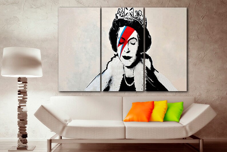 May include: A three-panel canvas print featuring a black and white portrait of Queen Elizabeth II with a red, blue, and white lightning bolt painted over her right eye. The queen is wearing a crown and a fur collar.